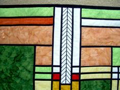 a close up of a stained glass window with green, orange and yellow designs on it