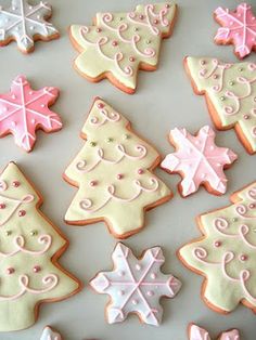 decorated christmas cookies on a table with pink and white icing, snowflakes and trees