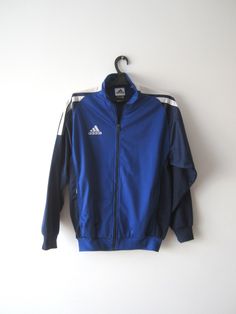 "Vintage Blue Adidas Jacket Blue Adidas Zipper Running Jacket Unisex Jogging Parka Blue Soccer Jacket Three Stripes Size Large Adidas Cardigan Label size: D 176; GB 34/36; F 16A Measurements: (lying flat) Length - 28.5\"/ 72.5 cm Shoulders: 20\"/ 51 cm Pit to pit: 22.5\"/ 57 cm Waist: 19.5\"/ 49.5 cm Sleeve: 22.5\"/ 57 cm Please check measurements to insure a proper fit. Remember to allow yourself some extra room for movement. You can compare these with something from your closet that fits you w Blue Sports Windbreaker For Fall, Winter Blue Windbreaker With Zipper Closure, Blue Long Sleeve Outerwear With Zipper Closure, Blue Long Sleeve Outerwear With Zipper, Blue Long Sleeve Outerwear For Outdoor, Blue Sportswear Windbreaker With Pockets, Blue Sportswear Track Jacket For Fall, Blue Track Jacket For Fall Sportswear, Blue Track Jacket For Fall