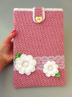 a woman's hand holding a pink crocheted purse with flowers on it