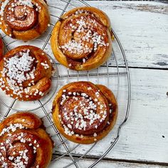 several pastries sitting on a wire rack with sugar sprinkled on top and one in the middle