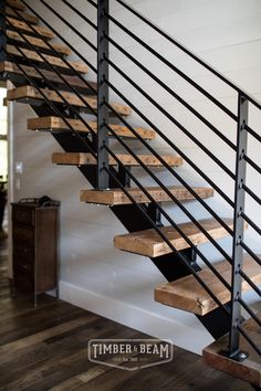 a stair case with wooden treads and black handrail in a home entryway