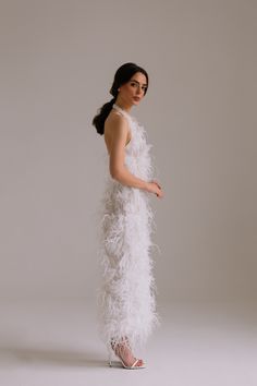 a woman in a white feather dress posing for the camera with her hand on her hip