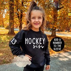 Hockey sis Sweatshirt, Custom Hockey Sister shirt, Hockey Sweatshirt, Hockey Sweater, Hockey gift,Personalized Hockey Sweatshirt, Hockey Tee ✨ Keep your little ones on trend with our hockey sis, brother or mom design.   Customization are allowed for this by adding a number to the sleeve! 📋 HOW TO ORDER: 1. Select the size (Size up for an oversized look) 2. Select the color 3. Select the quantity (Not sold as a set) 4. Add personalization if required 5.Add to Cart ("buy now" will take you direct Name Print Tops As Winter Gift, Winter Name Print Top As Gift, Black Long Sleeve Top As Gift, Black Long Sleeve Top As A Gift, Hockey Team Christmas Gift Ideas, Hockey Sister, Cricut Hockey Shirts, Hockey Mom Sweater, Hockey Sweater Cricut