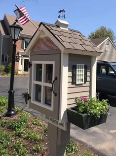 a small house with an american flag on the roof and flowers growing in pots next to it