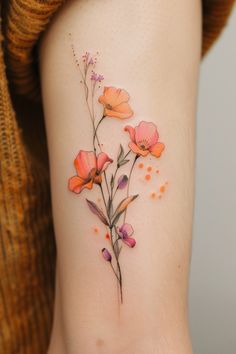 an orange flower tattoo on the side of a woman's leg with pink and purple flowers