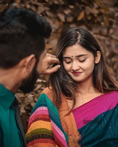 a man touching the forehead of a woman who is wearing a multicolored sari