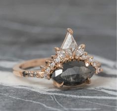 a close up of a diamond ring on a marble surface with white and black diamonds