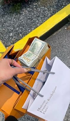 a person is holding scissors and money in a box