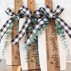 three wooden paddles decorated with black and white plaid bows on top of a kitchen counter