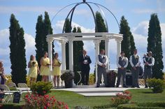 a group of people standing on top of a lush green field next to a gazebo