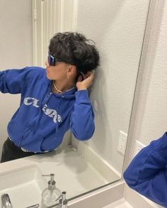 a woman in a blue hoodie taking a selfie in front of a mirror