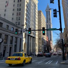 a yellow taxi stopped at an intersection in the middle of a city with tall buildings