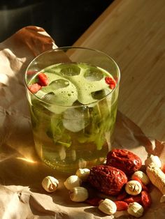 a glass filled with green liquid next to peanuts and other food on top of a piece of paper