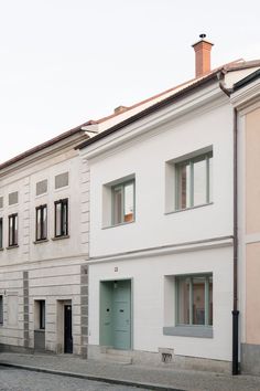 two white buildings with green doors and windows