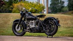 a black motorcycle parked on the side of a road near some grass and trees in the background