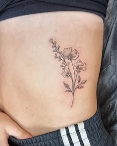 a woman's stomach with a flower tattoo on her side, and the bottom part of her belly