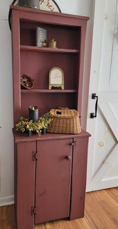 an old red bookcase with a basket on top and other items sitting on it