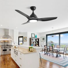 a ceiling fan is hanging in the middle of a kitchen with hardwood floors and large windows