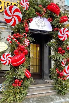 a christmas wreath with candy canes hanging from it's sides on the side of a building