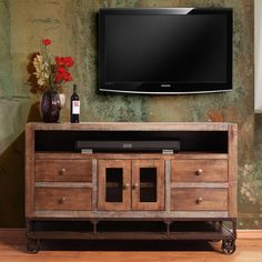 an entertainment center with a flat screen tv mounted on it's wall and two vases filled with flowers