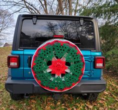 a green and red crocheted christmas wreath on the back of a blue jeep