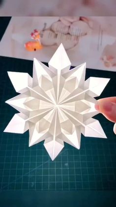 someone is making a snowflake out of paper