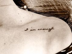 the back of a woman's neck with an inscription that reads i am enough