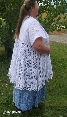 a woman standing in the grass wearing a white crochet top