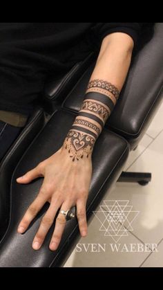 a woman's arm with tattoos on it and her hand resting on the back of a chair