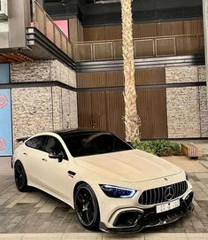 a white mercedes cla parked in front of a building with palm trees on the sidewalk