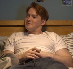 a man sitting on top of a bed in a bedroom