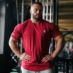 a man with his hands on his hips standing in front of a gym equipment rack