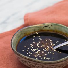 a bowl of sesame seed soup with a spoon in it on a red cloth next to a pink towel