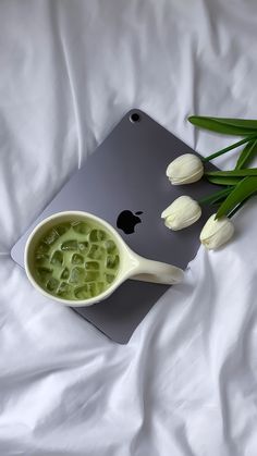 some white tulips sitting on top of a bed next to an apple laptop