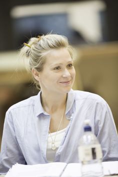 a woman sitting at a table with a bottle of water