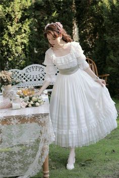 a woman in a white dress standing next to a table