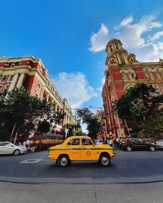 a yellow taxi cab driving down a street next to tall buildings