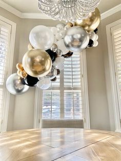 a table with many balloons hanging from it's ceiling in front of a chandelier