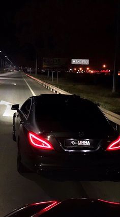 two cars driving down the road at night