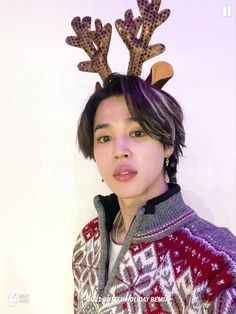 a woman with reindeer antlers on her head wearing an ugly sweater and looking at the camera