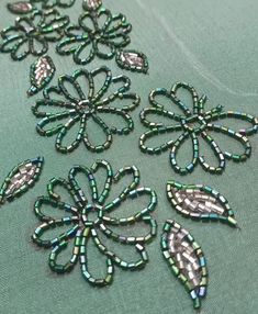 green and silver beaded fabric with flowers on it