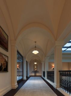 an empty hallway in a building with large windows and railings leading to the second floor