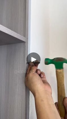 a person is holding a hammer to the side of a wall