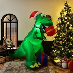 a large inflatable dinosaur sitting next to a christmas tree