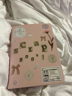 a pink scrap book with various stickers on it sitting on top of a bed