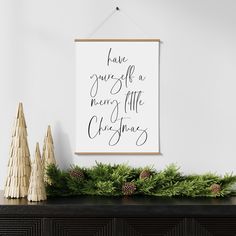 a christmas mantle with pine cones and evergreens on it, next to a framed poster