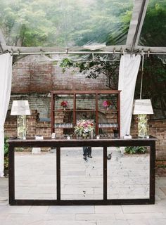 a table with two lamps on it in the middle of a room filled with white curtains