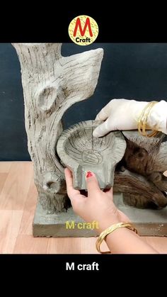 a person is making a sculpture out of wood and cement with their hands on the base