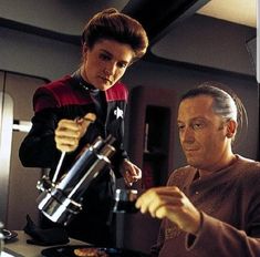 a man and woman are looking at something on the counter in a star trek ship